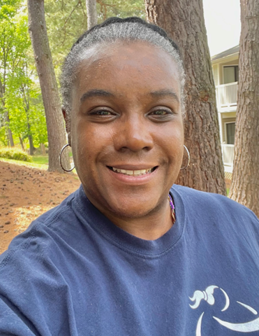 A Girls on the Run program coach smiles at the camera outdoors.